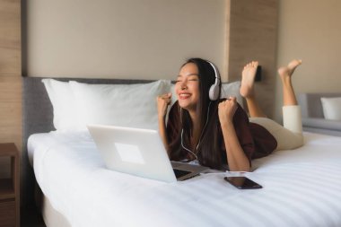 Bilgisayar ve kulaklık kullanan güzel Asyalı kadınların portresi.