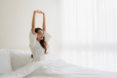 Portre güzel genç Asyalı kadınlar yatakta mutlu gülümsüyor.