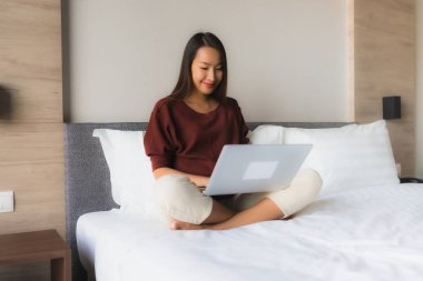 Bilgisayar ve cep telefonu kullanan güzel Asyalı genç kadınların portresi.