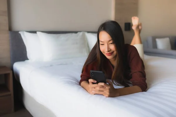 Portret mooie jonge Aziatische vrouwen met behulp van mobiele telefoon op bed — Stockfoto