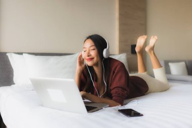 Bilgisayar ve kulaklık kullanan güzel Asyalı kadınların portresi.