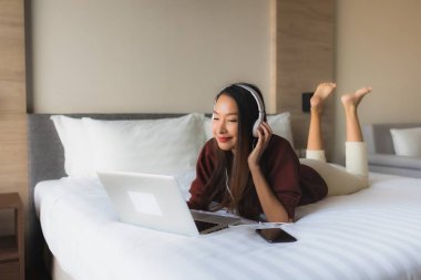 Bilgisayar ve kulaklık kullanan güzel Asyalı kadınların portresi.