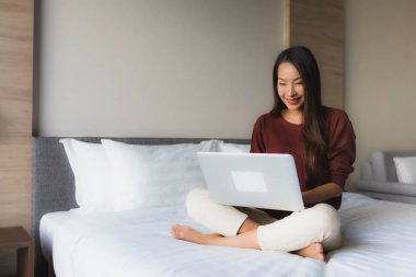 Bilgisayar ve cep telefonu kullanan güzel Asyalı genç kadınların portresi.