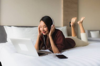 Bilgisayar ve kulaklık kullanan güzel Asyalı kadınların portresi.