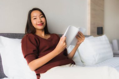 Yatakta kitap okuyan güzel Asyalı kadınların portresi.