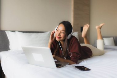 Bilgisayar ve kulaklık kullanan güzel Asyalı kadınların portresi.