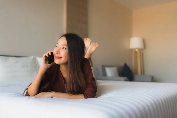 Porträt schöne junge asiatische Frauen mit Handy auf dem Bett — Stockfoto