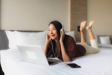 Bilgisayar ve kulaklık kullanan güzel Asyalı kadınların portresi.