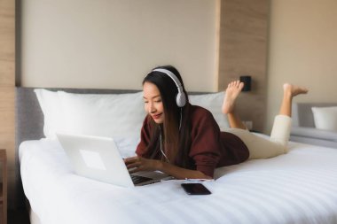 Bilgisayar ve kulaklık kullanan güzel Asyalı kadınların portresi.