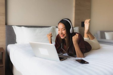 Bilgisayar ve kulaklık kullanan güzel Asyalı kadınların portresi.