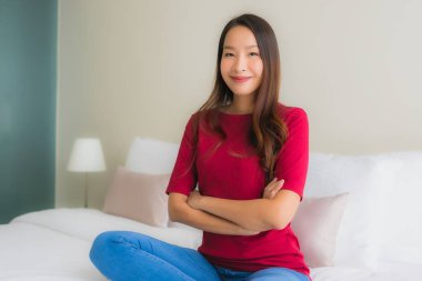 Portre güzel genç Asyalı kadınlar yatakta mutlu gülümsüyor.