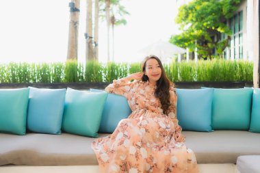 Güzel Asyalı genç kadınların portresi. Mutlu bir gülümseme. Kanepeye otur.