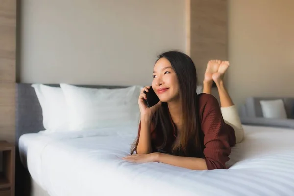 Porträt schöne junge asiatische Frauen mit Handy auf dem Bett — Stockfoto