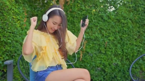 Πλάνα Από Όμορφη Ασιατική Γυναίκα Ακούγοντας Μουσική Ακουστικά Στον Κήπο — Αρχείο Βίντεο