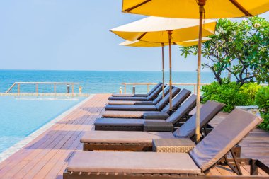 Dışarıda yüzme havuzu etrafında güzel boş bir sandalye şemsiyesi.