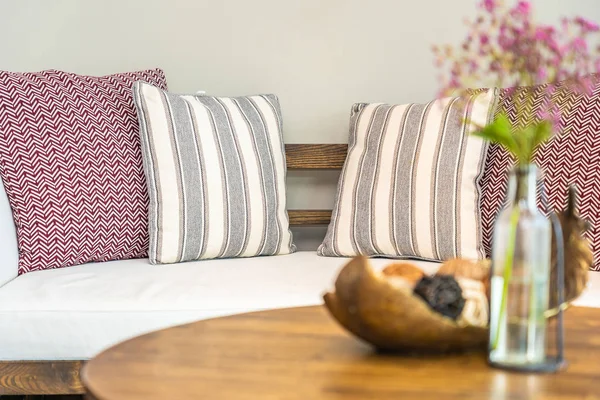 Цветочная ваза на столе с подушкой на диване украшения интерьера — стоковое фото
