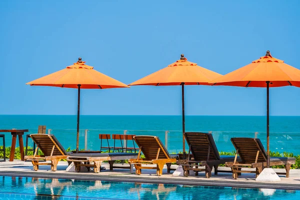 Parapluie et chaise autour de la piscine extérieure près de la mer dans chaud — Photo