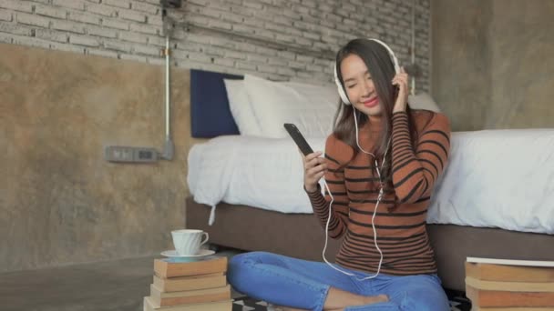 美しいアジアの女性がヘッドフォンで音楽を聴いている映像です — ストック動画
