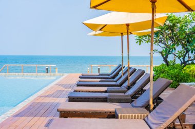 Dışarıda yüzme havuzu etrafında güzel boş bir sandalye şemsiyesi.