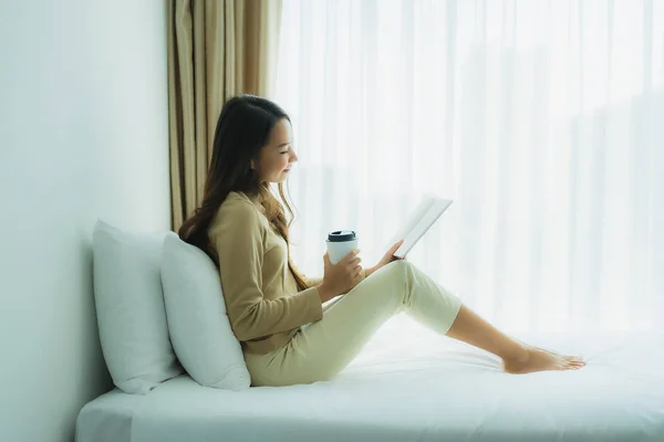 Junge asiatische Frau mit Kaffeetasse und Buch lesen — Stockfoto