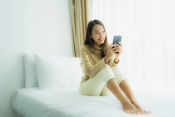 Giovane donna asiatica utilizzando cellulare smart phone sul letto — Foto Stock