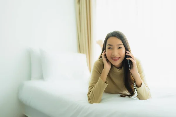Joven asiático mujer usando móvil inteligente teléfono en cama — Foto de Stock
