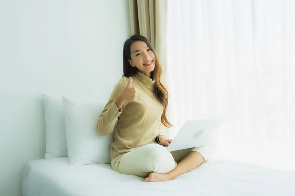 Молодая азиатка использует ноутбук на кровати — стоковое фото