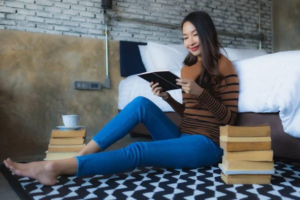 Elinde kahve fincanı olan ve kitap okuyan Asyalı genç bir kadın. — Stok fotoğraf