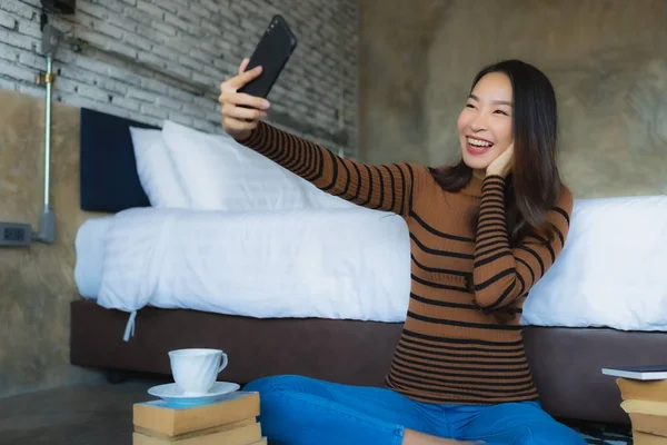 Giovane donna asiatica utilizzando smart telefono cellulare con leggere libro e co — Foto Stock