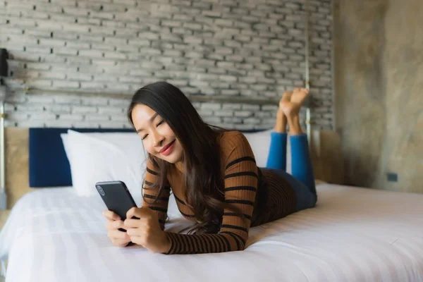 Молода азіатська жінка використовує мобільний смартфон на ліжку — стокове фото
