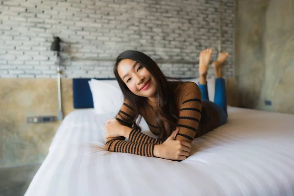 Fiatal ázsiai nő boldog mosoly pihenjen az ágyon a hálószobában — Stock Fotó
