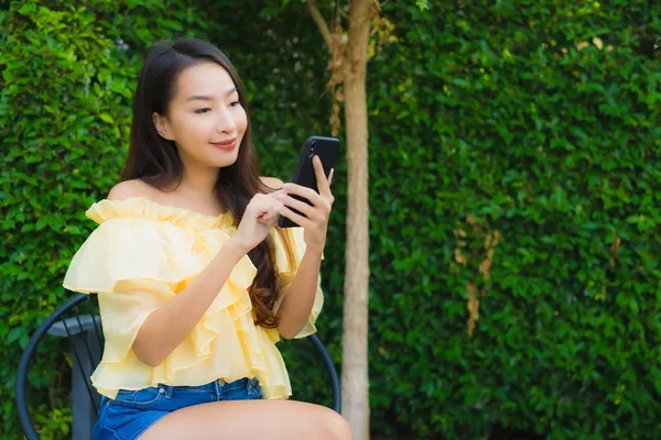 Fiatal ázsiai nő használ okos mobiltelefon körül szabadtéri természet — Stock Fotó