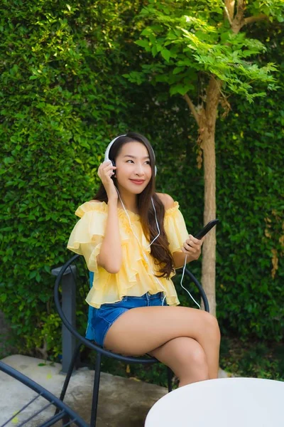 Mladá asijská žena pomocí chytrého mobilního telefonu se sluchátkem pro li — Stock fotografie