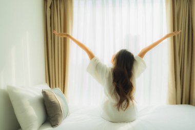 Genç Asyalı mutlu gülümseme. Yatak odasında rahatla.