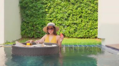 Güzel Asyalı bir kadının oteldeki havuzda dinlenirken çekilmiş görüntüleri.