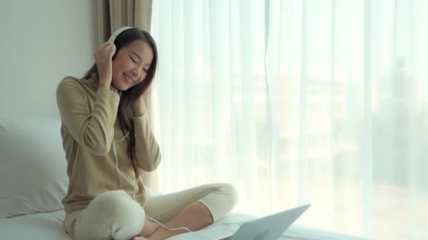 美しいアジアの女性がヘッドフォンで音楽を聴いている映像です — ストック動画