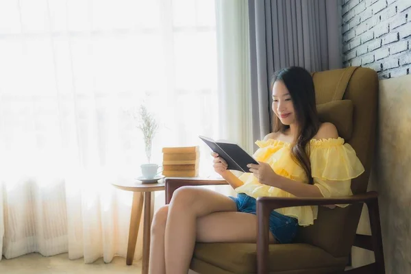 Portrait young asian woman sit on sofa chair and read book with — Stock Photo, Image
