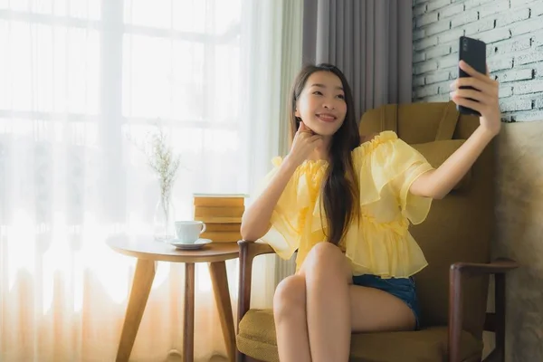 Porträtt ung asiatisk kvinna med mobiltelefon med kaffekopp och — Stockfoto