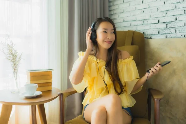 Портрет молодої азіатки сидить на стільці слухати музику з мобільним — стокове фото