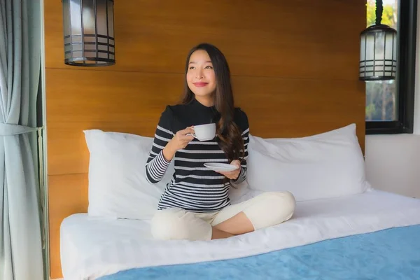 Porträt junge asiatische Frau auf Bett im Schlafzimmer Interieur mit Kaffee — Stockfoto