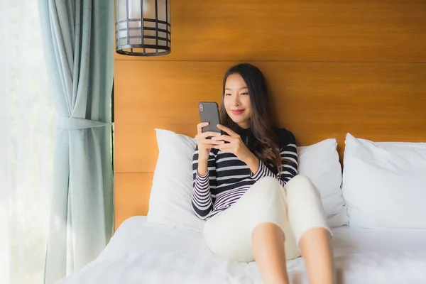 Portrait jeune femme asiatique en utilisant le téléphone mobile intelligent sur le lit en être — Photo