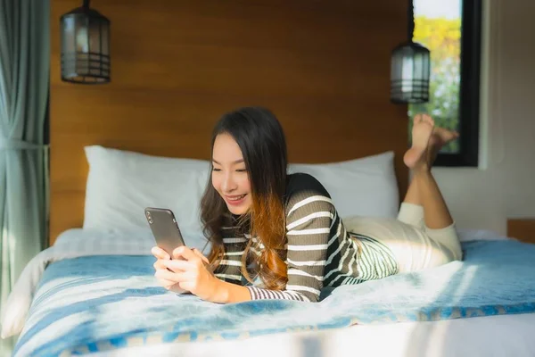 Portrait jeune femme asiatique en utilisant le téléphone mobile intelligent sur le lit en être — Photo