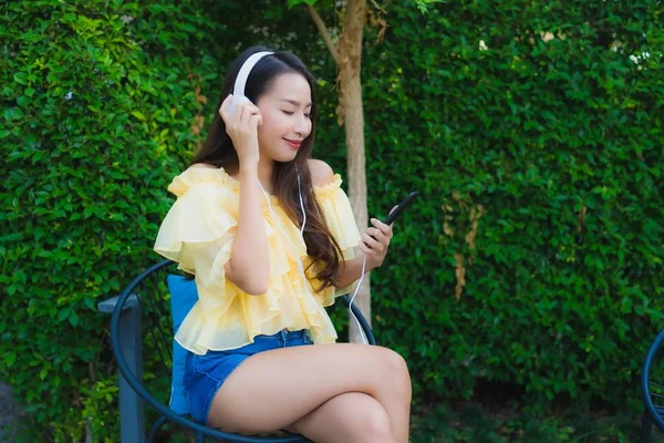 Młoda Azji kobieta za pomocą inteligentny telefon komórkowy ze słuchawką dla li — Zdjęcie stockowe