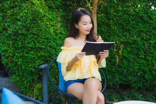 年轻的亚洲女人阅读关于室外花园自然的书籍 — 图库照片