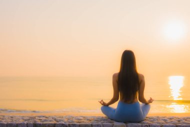 Genç Asyalı kadının portresi, deniz kıyısı okyanusunda meditasyon yapıyor. 