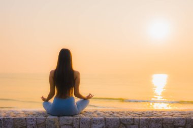 Genç Asyalı kadının portresi, deniz kıyısı okyanusunda meditasyon yapıyor. 