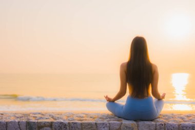 Genç Asyalı kadının portresi, deniz kıyısı okyanusunda meditasyon yapıyor. 
