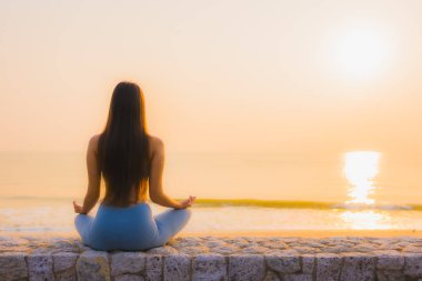 Genç Asyalı kadının portresi, deniz kıyısı okyanusunda meditasyon yapıyor. 