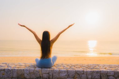 Genç Asyalı kadının portresi, deniz kıyısı okyanusunda meditasyon yapıyor. 