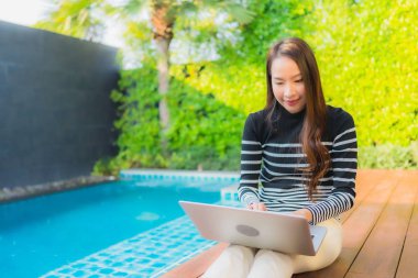 Dışarıda dizüstü bilgisayar kullanan Asyalı genç bir kadının portresi. 